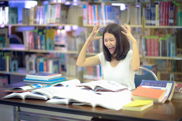 Image: Distressed student surrounded by books